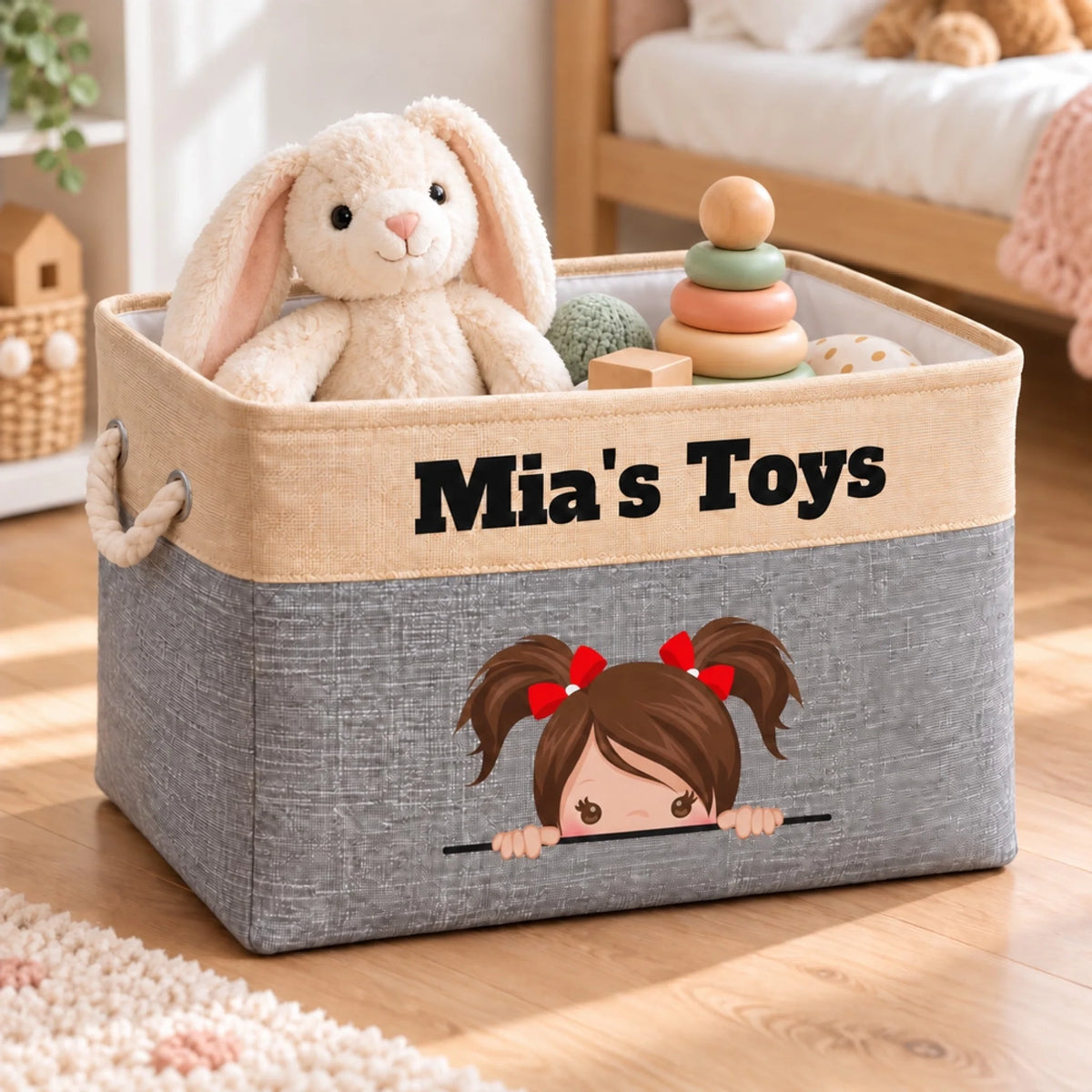 Grey personalized toy box with the name Mia and a cartoon girl with brown pigtails, holding toys in a child's room